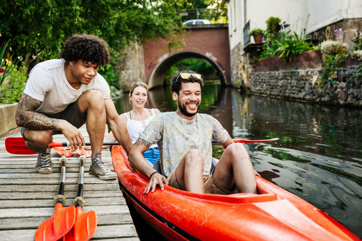 A group of friends getting ready to go paddling in kayaks together on the canal