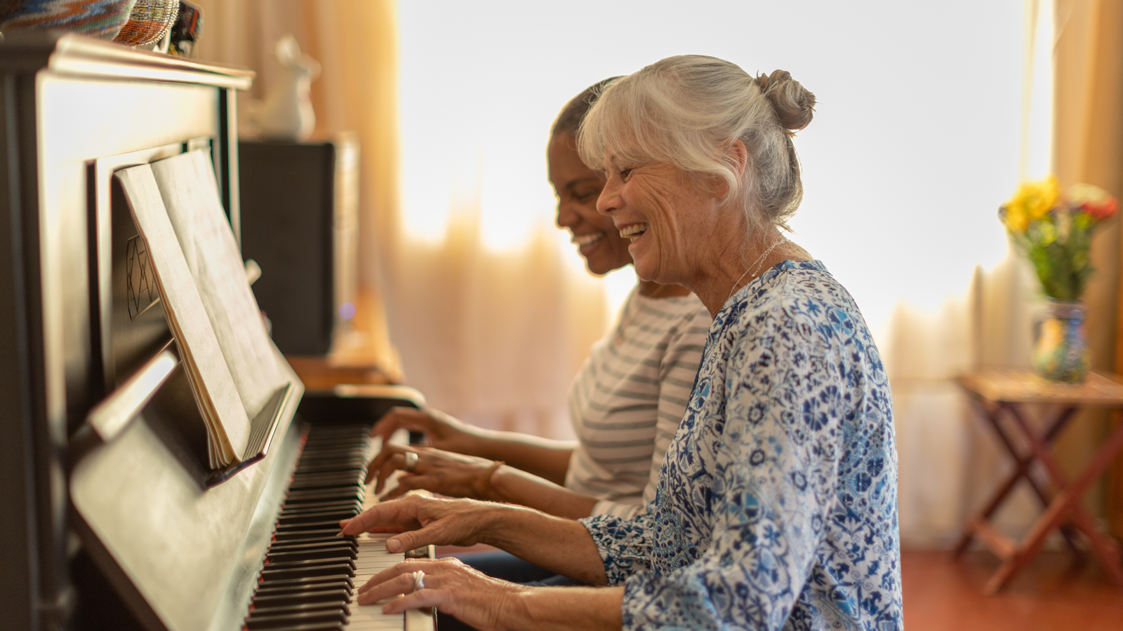 Two women playing the piano together at home