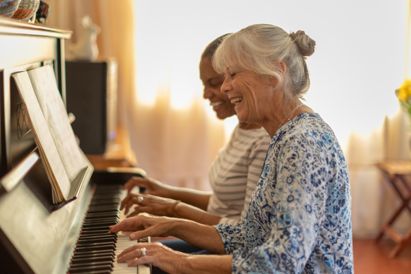 Dos mujeres tocando el piano juntas en casa