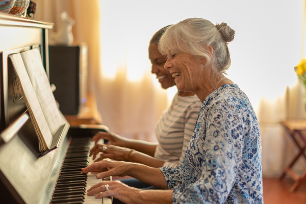 Two women playing the piano together at home