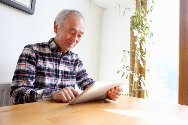 Hombre mayor usando una tableta en una mesa