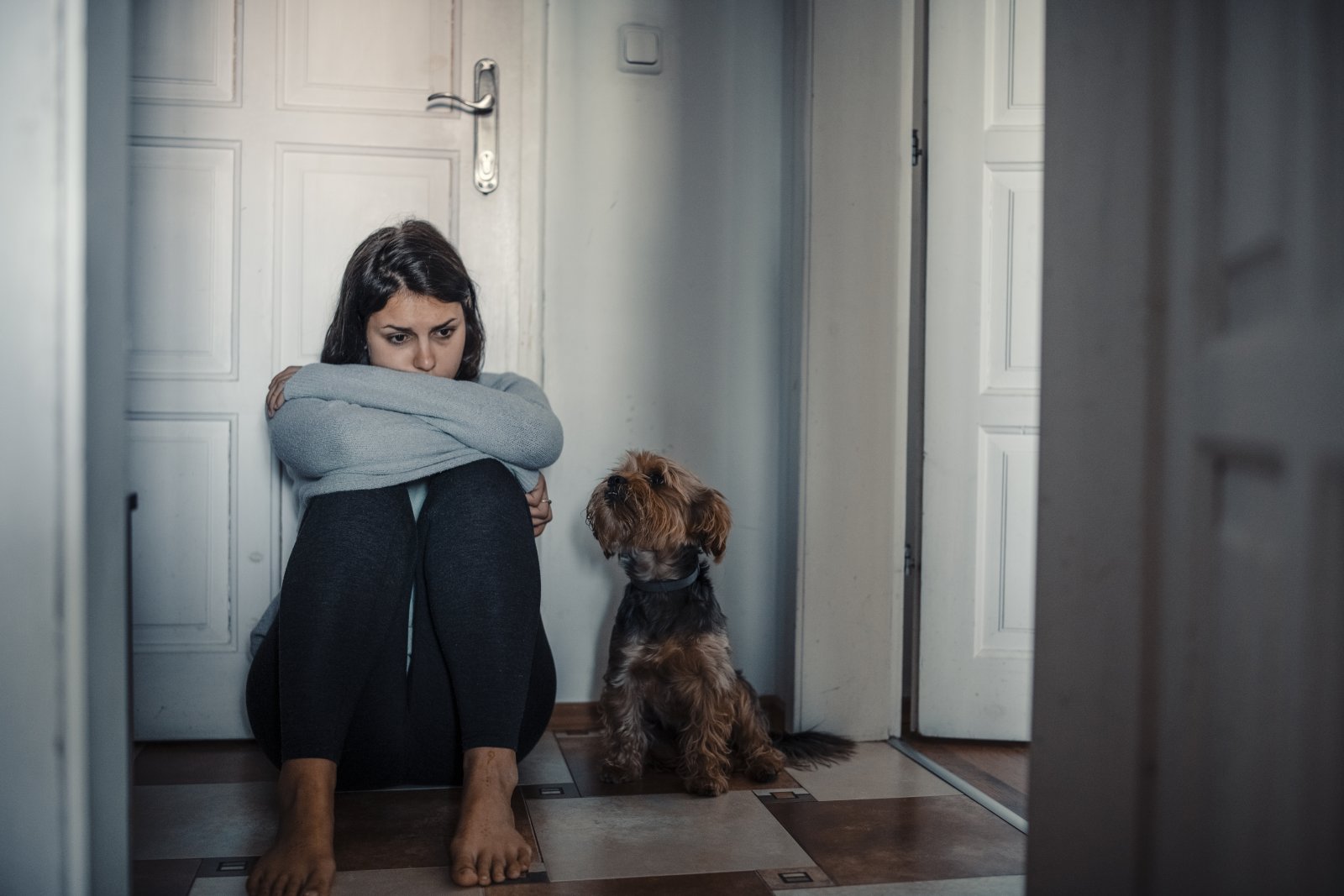 Woman With A Mental Health Problems Is Sitting Exhausted On The Floor With Her Dog Next To Her