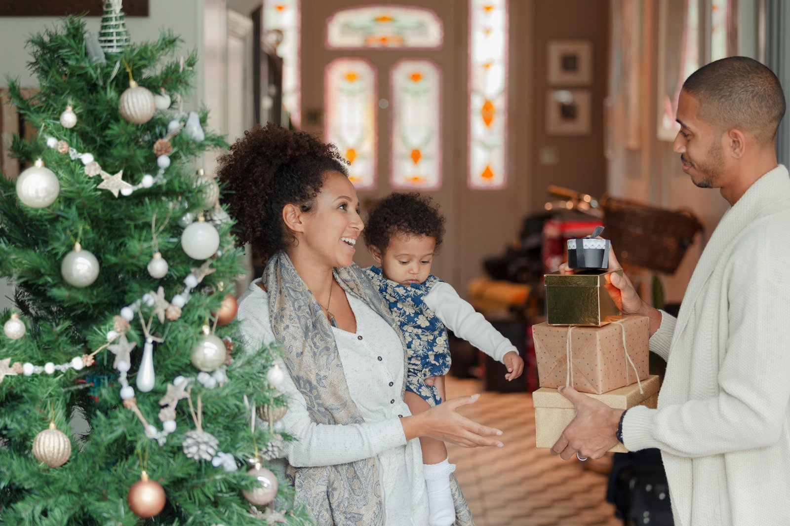 Family standing beside a Christmas Tree holding gifts