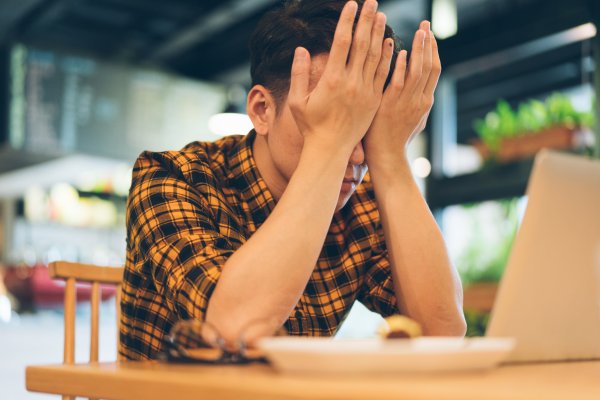 Exhausted Young Man Rubbing Eyes In Cafe