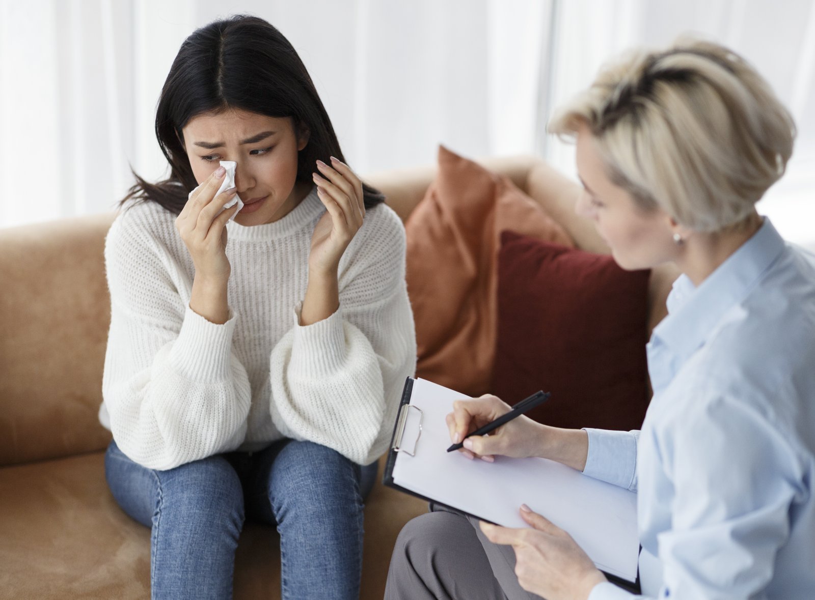 Asian Woman Crying Talking With Psychologist Sitting In Office