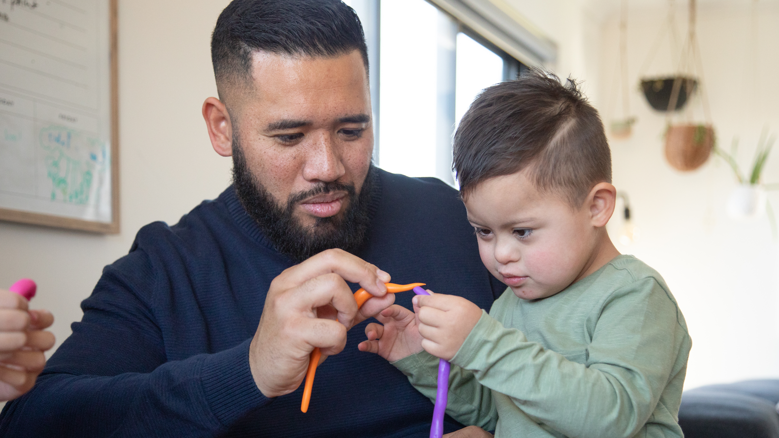 Magellan Healthcare | Father and son with down syndrome sit at table playing