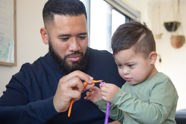 Magellan Healthcare | Father and son with down syndrome sit at table playing